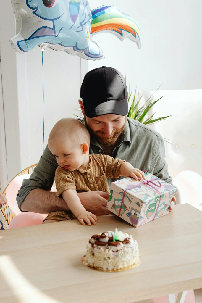 Papa mit Baby auf dem Arm am Geburtstagstisch